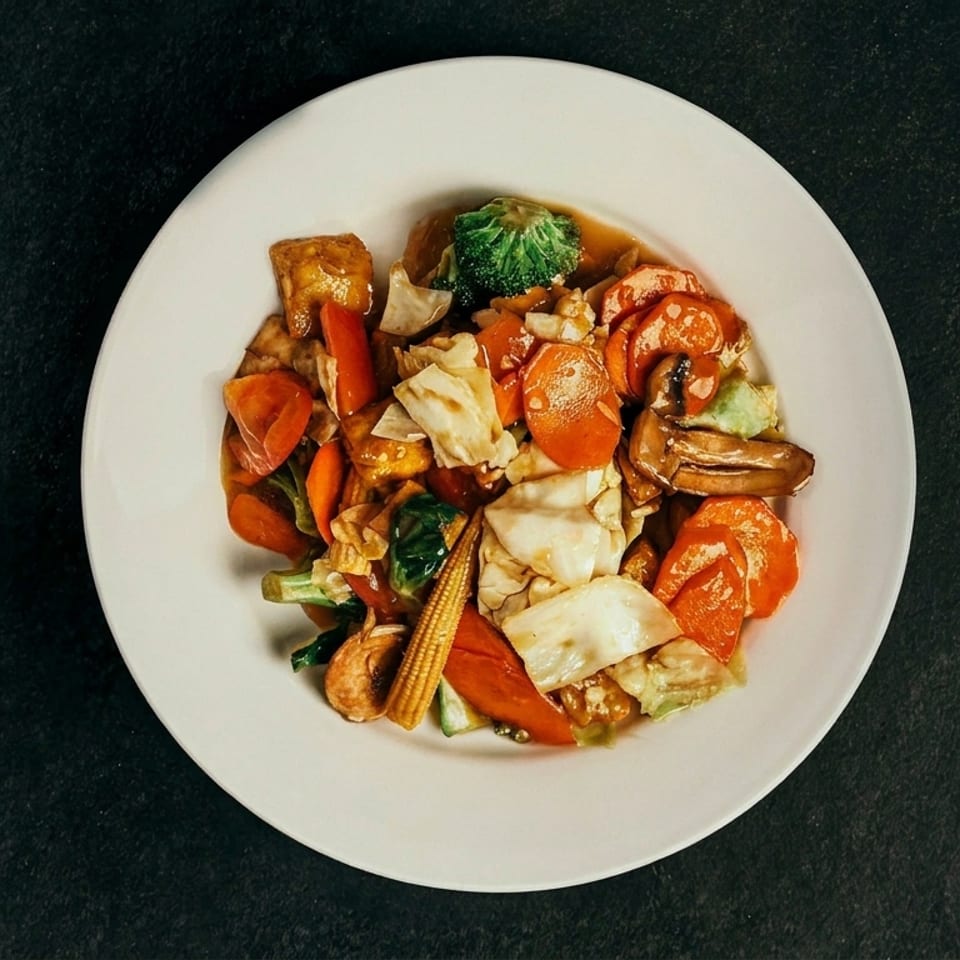 A colorful stir-fry with carrots, cabbage, broccoli, mushrooms, and baby corn on a white plate.